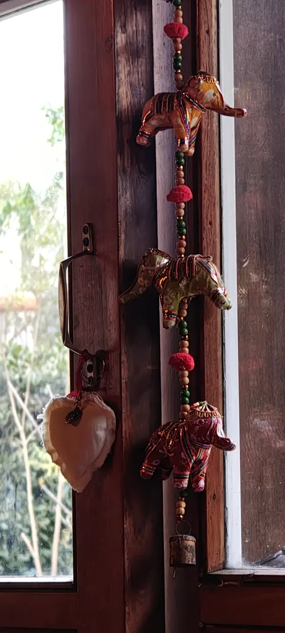 Adorno de elefantes colgado junto a una ventana de madera
