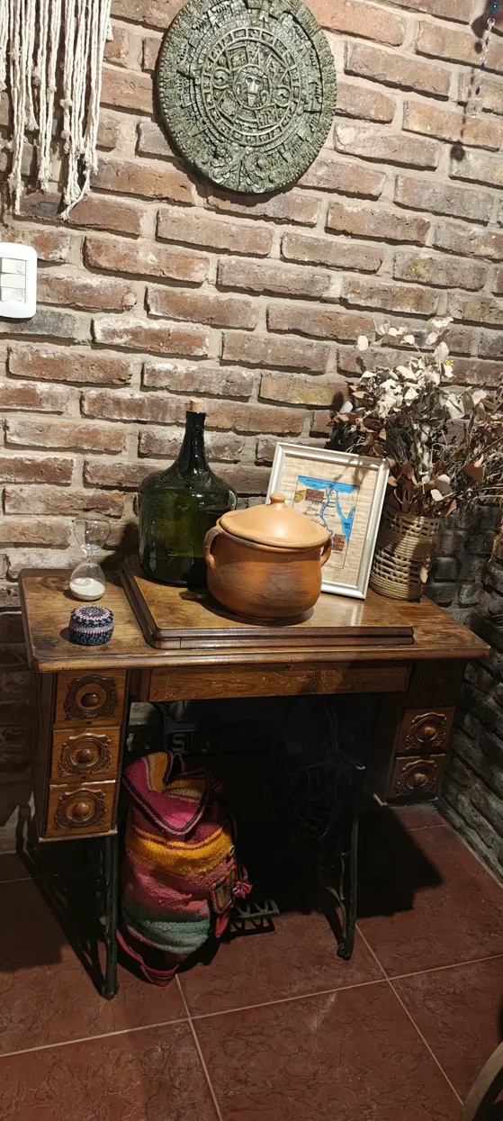 Mesa de madera, objetos y plantas junto a una pared de ladrillo