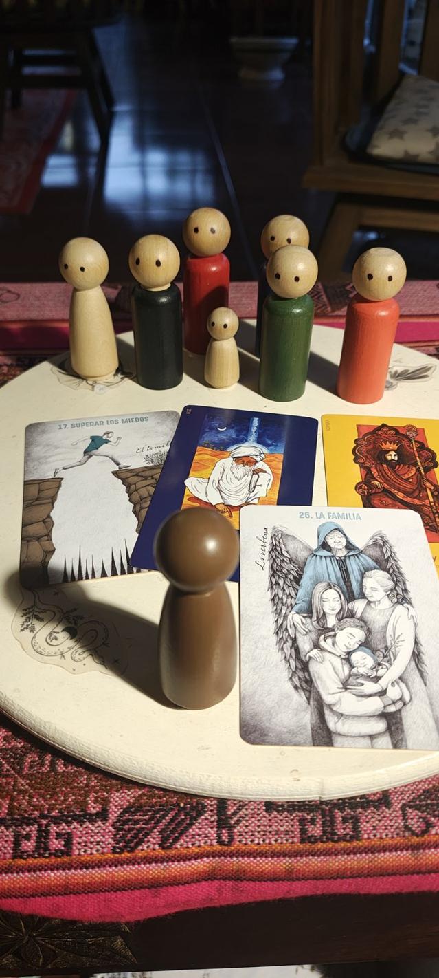 Muñecos de madera y cartas sobre una mesa con un aguayo, preparados para una sesión
