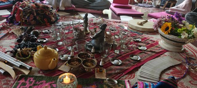Mesa con tetera, tazas, velas, flores y cartas, preparada para una Ceremonia del Té