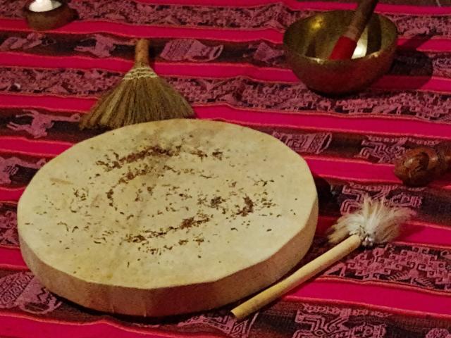 Tambor, cuenco tibetano y baquetas sobre un aguayo, preparados para un masaje sonoro